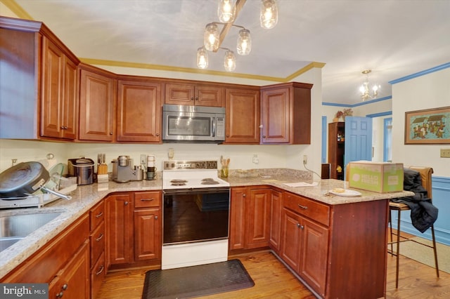 kitchen with hanging light fixtures, light wood-type flooring, an inviting chandelier, and electric stove