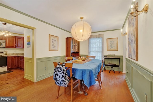 dining area with light wood-type flooring and crown molding