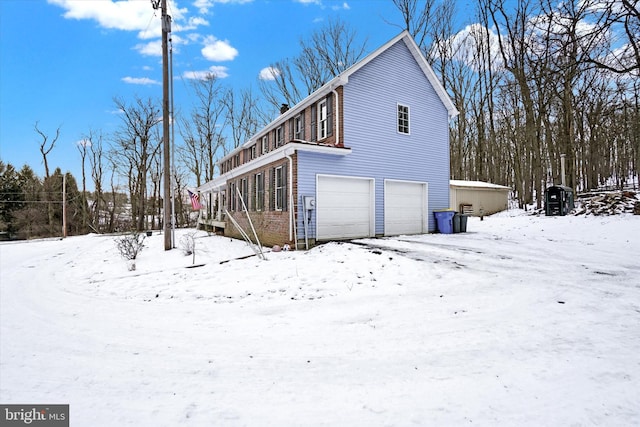 view of snow covered exterior featuring a garage and a chimney