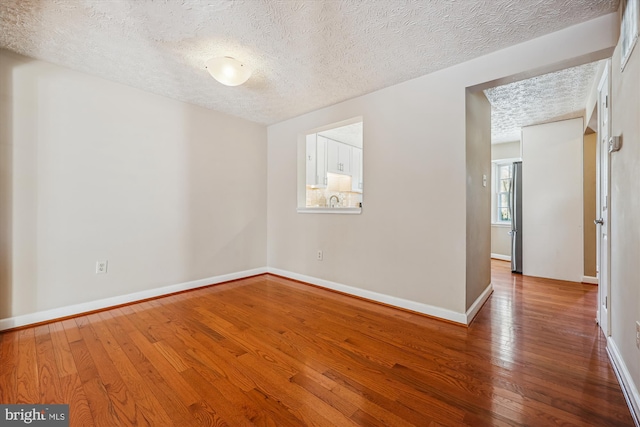 unfurnished room with a textured ceiling and hardwood / wood-style flooring