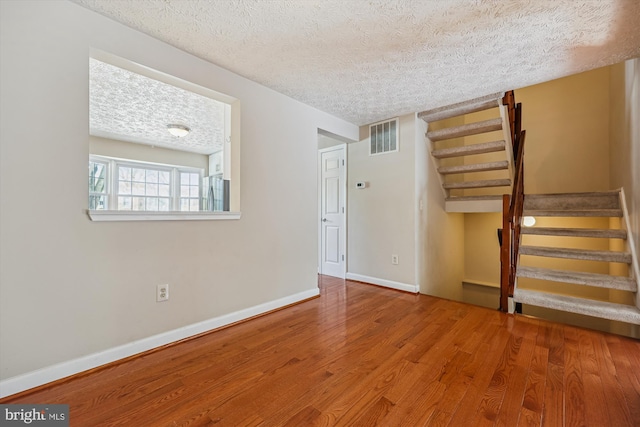 spare room featuring hardwood / wood-style flooring and a textured ceiling