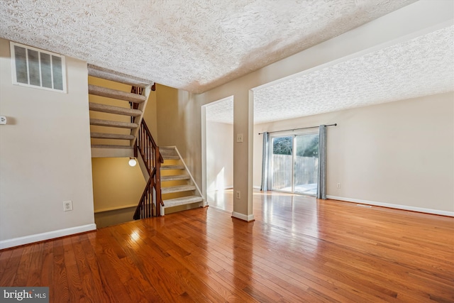 unfurnished living room with wood-type flooring and a textured ceiling