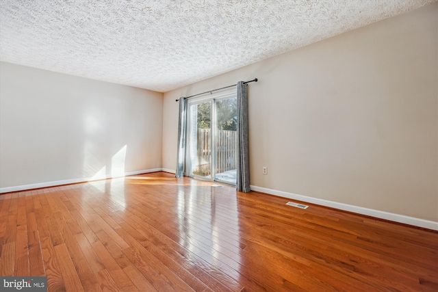 empty room with a textured ceiling and light wood-type flooring