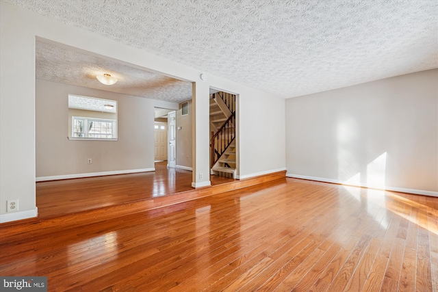 unfurnished living room with wood-type flooring and a textured ceiling