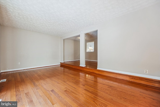 spare room with a textured ceiling and hardwood / wood-style floors