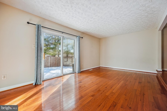 empty room with hardwood / wood-style flooring and a textured ceiling