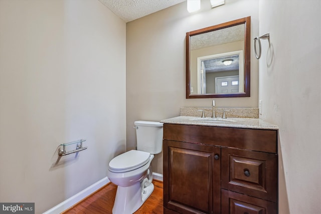 bathroom with toilet, hardwood / wood-style flooring, a textured ceiling, and vanity