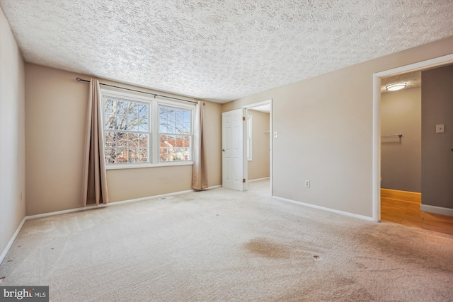 empty room with a textured ceiling and light carpet