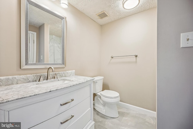 bathroom featuring a textured ceiling, vanity, and toilet