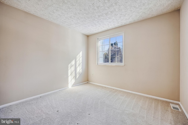 unfurnished room featuring a textured ceiling and carpet