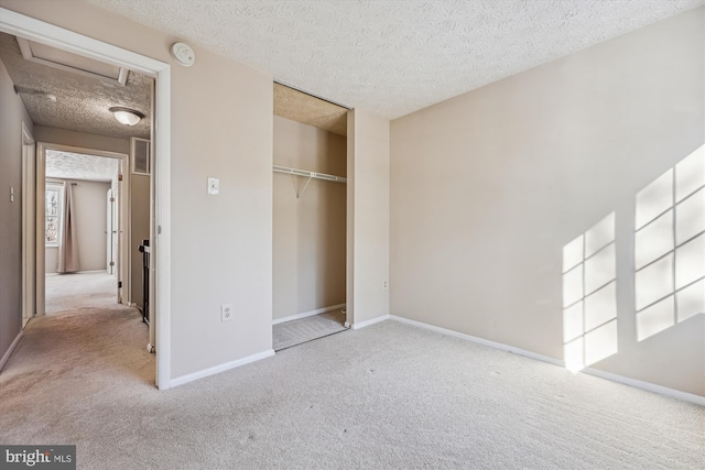 unfurnished bedroom with light colored carpet, a closet, and a textured ceiling