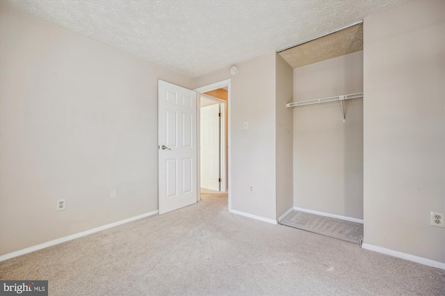 unfurnished bedroom featuring a textured ceiling, a closet, and light carpet