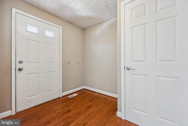 foyer entrance with a textured ceiling and light hardwood / wood-style floors