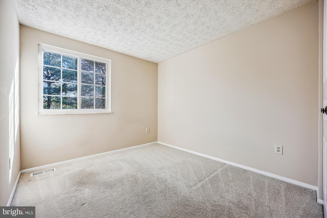 spare room with a textured ceiling and carpet flooring