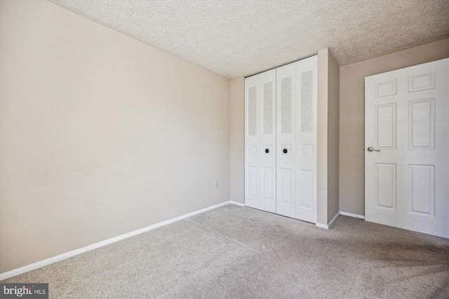 unfurnished bedroom with a textured ceiling, a closet, and light carpet