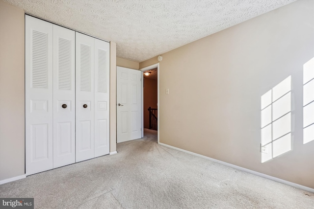 unfurnished bedroom featuring light colored carpet, a closet, and a textured ceiling