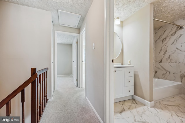 hall with a textured ceiling and light colored carpet