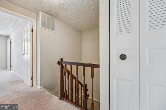 corridor featuring a textured ceiling and carpet floors