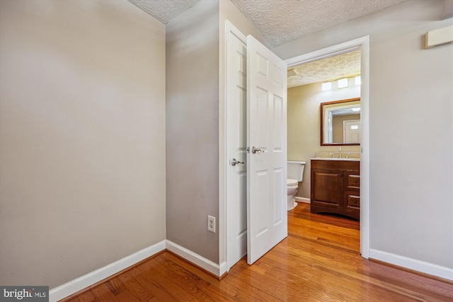 corridor featuring sink, a textured ceiling, and light hardwood / wood-style floors