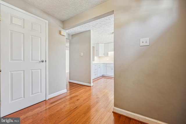 hallway featuring a textured ceiling and light hardwood / wood-style floors