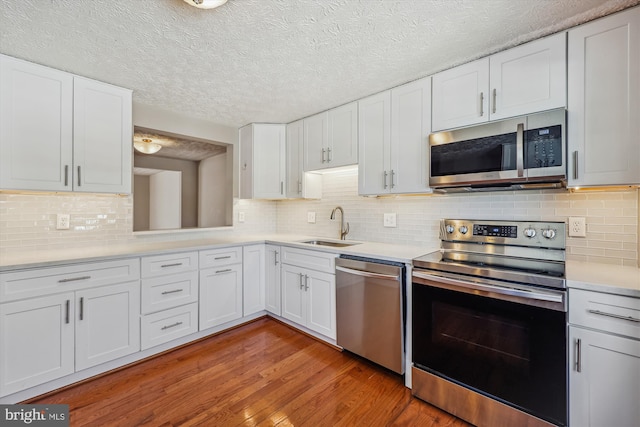 kitchen featuring sink, white cabinetry, light hardwood / wood-style flooring, backsplash, and appliances with stainless steel finishes