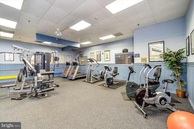 gym featuring ceiling fan, a drop ceiling, and carpet floors