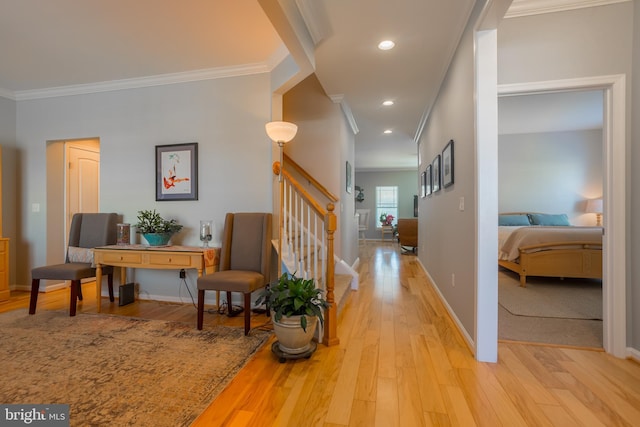 corridor with ornamental molding and light hardwood / wood-style flooring