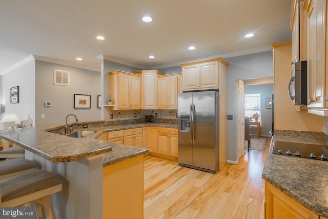 kitchen featuring appliances with stainless steel finishes, sink, a breakfast bar area, kitchen peninsula, and light brown cabinets