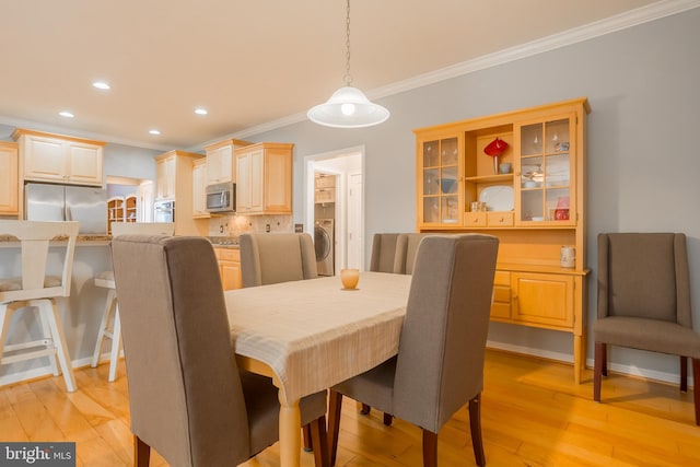 dining room with washer / clothes dryer, light hardwood / wood-style flooring, and ornamental molding