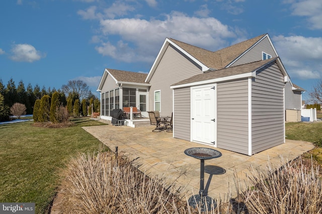 rear view of house featuring a lawn, a sunroom, and a patio