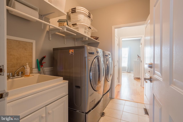 laundry area with cabinets, washing machine and dryer, sink, and light tile patterned floors