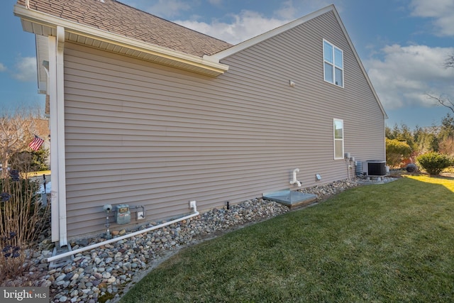 view of side of property with a yard and central AC unit