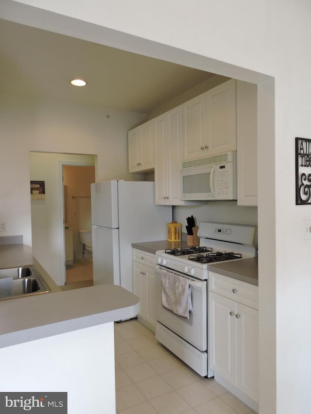 kitchen featuring white cabinets, light tile patterned flooring, white appliances, and sink