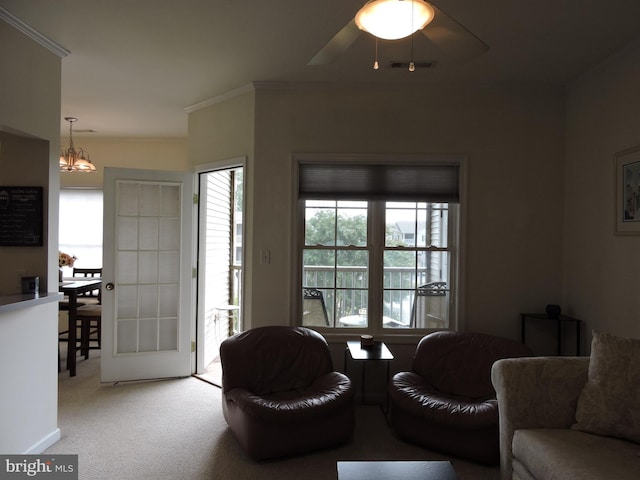 living room with carpet flooring, ceiling fan with notable chandelier, and crown molding