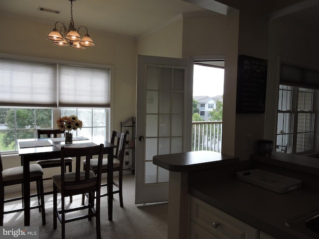 kitchen featuring carpet flooring, ornamental molding, hanging light fixtures, and an inviting chandelier