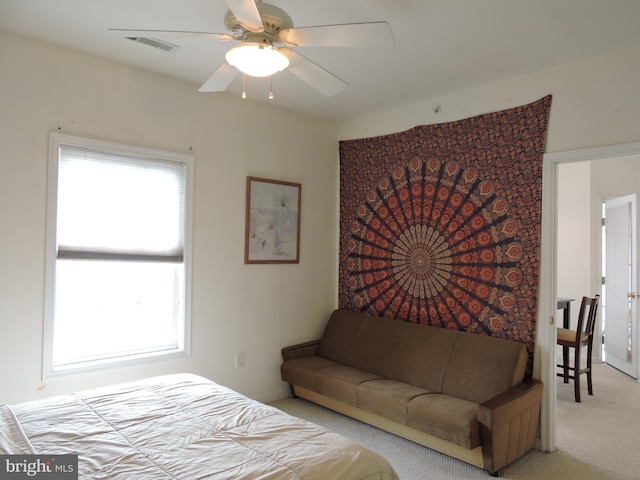 bedroom with ceiling fan, light carpet, and multiple windows