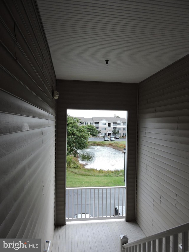 doorway to outside featuring a water view and wooden walls