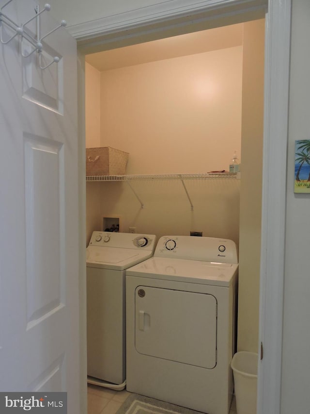 laundry area with light tile patterned floors and washer and clothes dryer