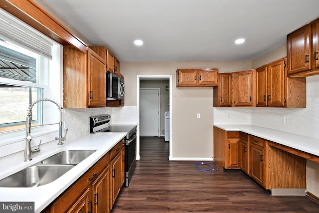 kitchen with appliances with stainless steel finishes, washer / clothes dryer, dark wood-type flooring, sink, and backsplash