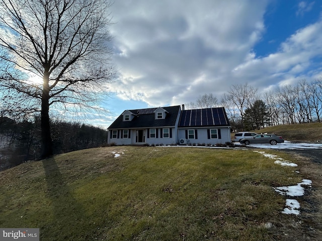 cape cod home with solar panels and a front yard