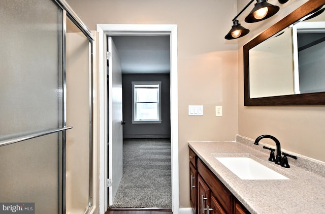 bathroom featuring a shower with shower door and vanity