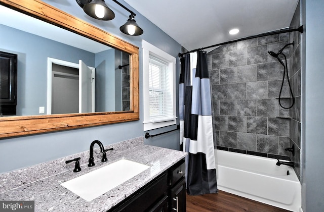 bathroom with hardwood / wood-style flooring, vanity, and shower / bath combo with shower curtain