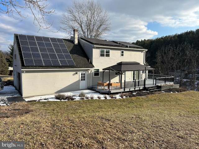 back of house featuring a yard, solar panels, and a wooden deck