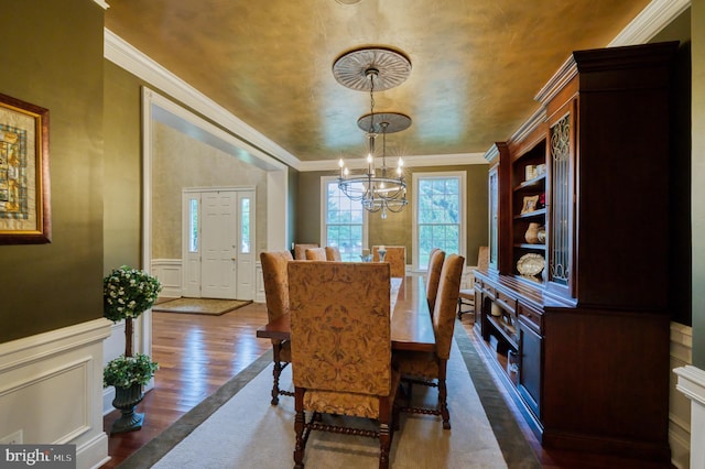 dining space with ornamental molding, dark wood-type flooring, and a notable chandelier