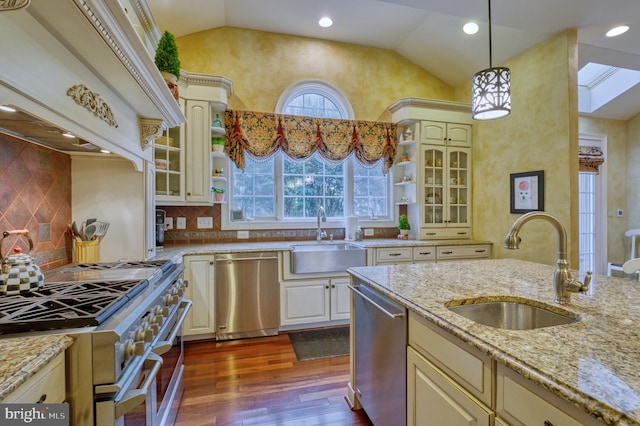 kitchen with light stone countertops, appliances with stainless steel finishes, sink, and decorative light fixtures