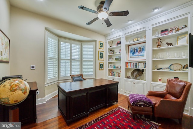 home office featuring built in shelves, dark hardwood / wood-style floors, and ceiling fan