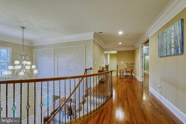 hallway featuring wood-type flooring, ornamental molding, and an inviting chandelier