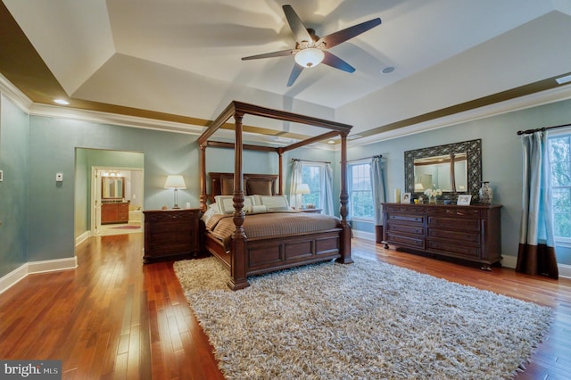 bedroom with dark hardwood / wood-style flooring, crown molding, multiple windows, and a tray ceiling