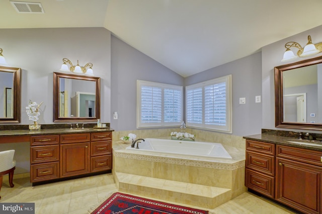 bathroom featuring lofted ceiling, vanity, tile patterned flooring, and tiled tub