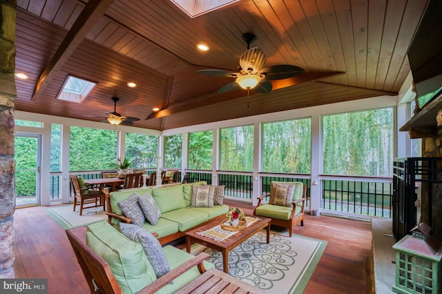 sunroom / solarium with vaulted ceiling with skylight, wooden ceiling, and ceiling fan